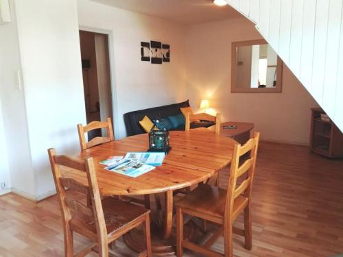 een houten eettafel met stoelen en een spiegel bij Bel appartement 6 personnes proche La Bresse in Cornimont