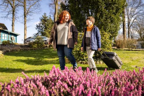 two women walking through a garden with pink flowers at Hotel Ehlers in Schneverdingen