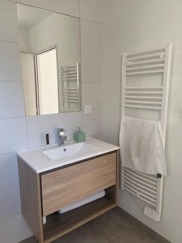 une salle de bain blanche avec un lavabo et un miroir dans l'établissement Le Sancta Cécilia, à Sainte-Cécile