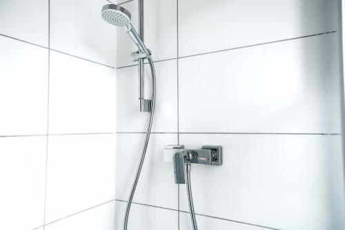 a shower in a white tiled bathroom at 50qm Apartment in Krefeld zentral gelegen mit hohen Decken - BEUYS Apartments - Krefeld in Krefeld