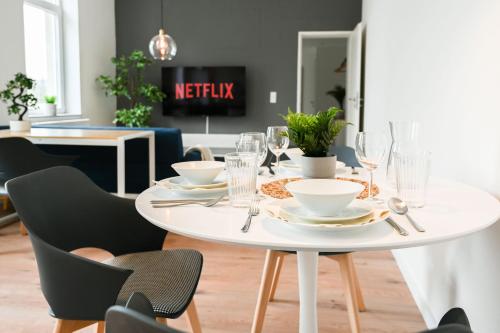 een witte eettafel met borden en bestek bij 50qm Apartment in Krefeld zentral gelegen mit hohen Decken - BEUYS Apartments - Krefeld in Krefeld