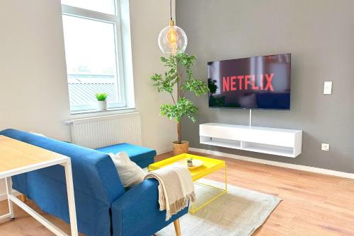 a living room with a blue couch and a tv at 50qm Apartment in Krefeld zentral gelegen mit hohen Decken - BEUYS Apartments - Krefeld in Krefeld