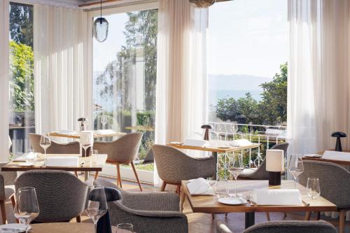 un restaurante con mesas, sillas y ventanas grandes en Hotel Haus am See en Nonnenhorn