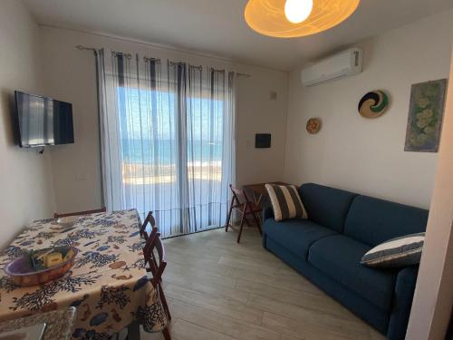 a living room with a blue couch and a table at La Porta sul Lungomare in Castelsardo