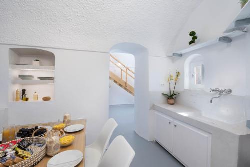 a white kitchen with a sink and a table at Red beach Harmony Suites Stone house in Akrotiri