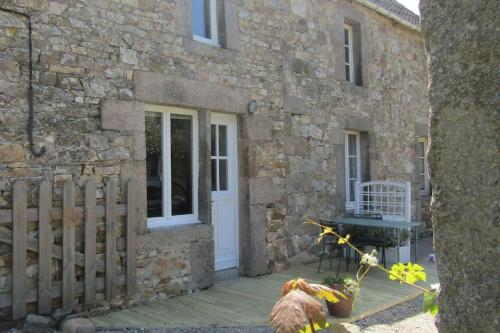 ein Steinhaus mit einer weißen Tür und einem Zaun in der Unterkunft Petite maison entre mer et campagne in Les Pieux