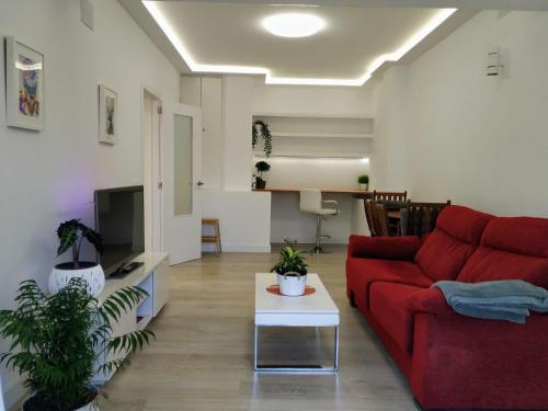 a living room with a red couch and a tv at Casa con jardín, 1 habitación, barbacoa in Collado Mediano