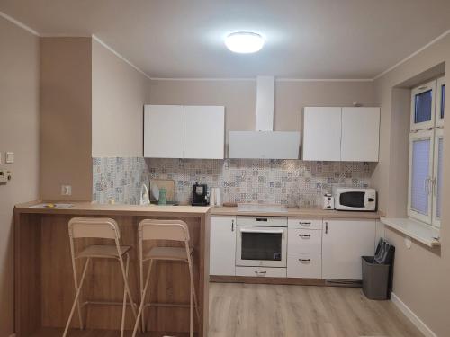 eine Küche mit weißen Schränken und einer Theke mit Stühlen in der Unterkunft Apartament na Wąskiej in Bydgoszcz