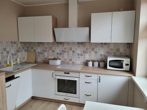 uma cozinha com armários brancos e um micro-ondas em Apartament na Wąskiej em Bydgoszcz
