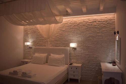 オルノスにあるカーサ ビアンカの白いベッドとレンガの壁が備わるベッドルーム1室が備わります。