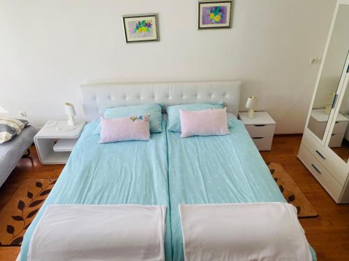 een slaapkamer met een blauw bed met 2 roze kussens bij Apartment Zvečaj in Ðakovo
