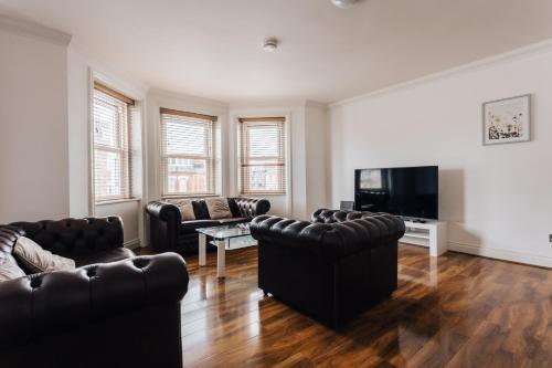 a living room with leather furniture and a flat screen tv at Top quality beach front apartment sleep up to 7 guests in Bournemouth
