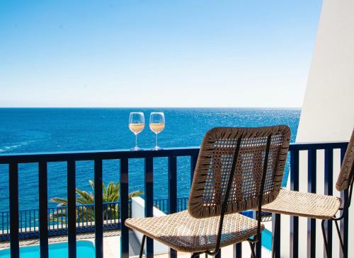 two glasses of wine sitting on a balcony with the ocean at FRONTLINE VILLA 26, Modern Coastal Design with Amazing Views in Puerto Calero