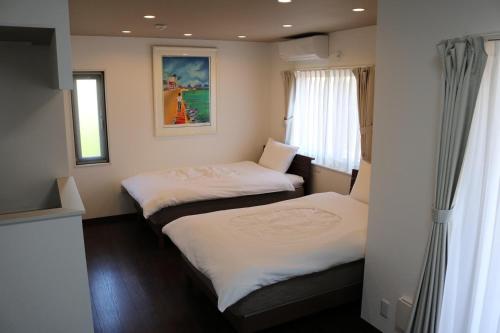 two beds in a small room with a window at ペンションニライカナイ in Awaren