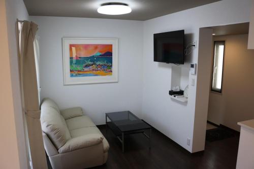 ein Wohnzimmer mit einem Sofa und einem TV in der Unterkunft ペンションニライカナイ in Awaren