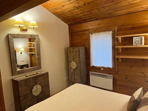1 dormitorio con cama, espejo y ventana en Cabaña de madera Vall D Incles Parking y Wifi Gratis, en Incles