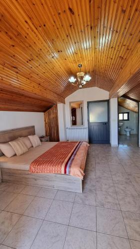 a bedroom with a large bed with a wooden ceiling at Kallmet Villa in Kalmet