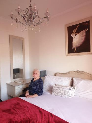 una mujer mayor sentada en una cama en Angel's Corner en Ciudad del Cabo