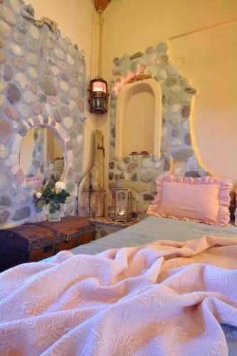 a bedroom with a large bed with a stone wall at Archontiko Art Hotel in Galaxidhion