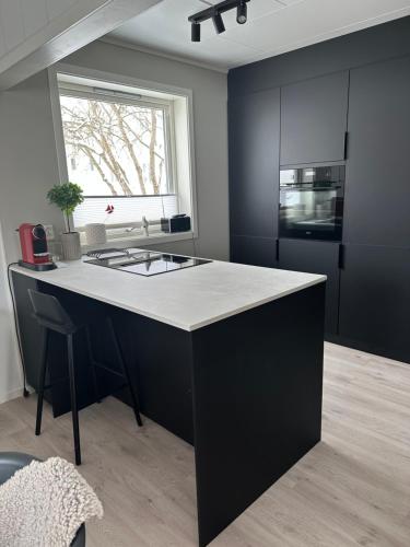 Lofoten Kabelvåg-small apartment في كابلفونغ: مطبخ مع جزيرة سوداء وبيضاء في الغرفة