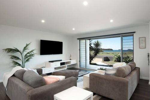 ein Wohnzimmer mit einem großen Sofa und einem TV in der Unterkunft Absolute Waterfront, Amazing Views, Maloneys Beach in Maloney's Beach