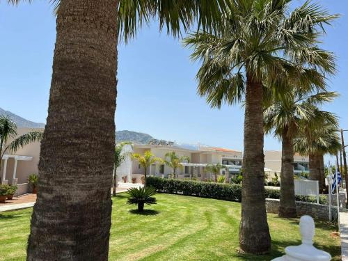 a lawn with palm trees in front of a building at Argiri Apartments & Suites in Georgioupolis