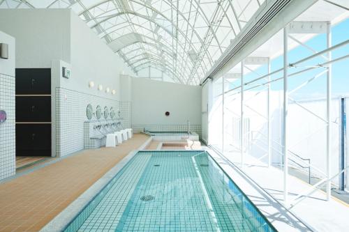 una piscina coperta con soffitto in vetro di INN THE PARK Fukuoka a Fukuoka