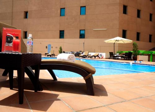 هوليداي إن - العليا في الرياض: مسبح بطاوله ومقعد بجانب مبنى