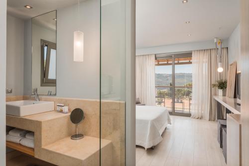 a bathroom with a sink and a bed and a mirror at Ino Hotel & Suites in Samos