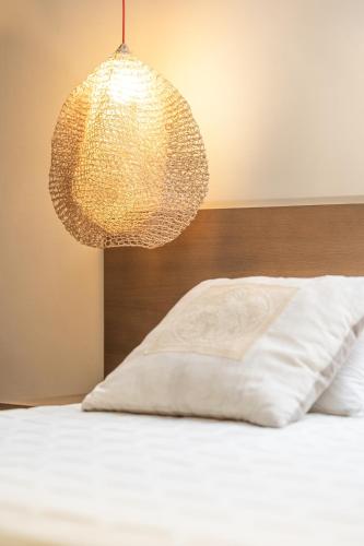 a bed with a white pillow and a lamp at Ino Hotel & Suites in Samos