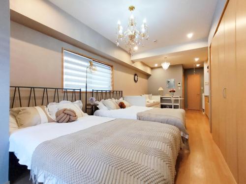 2 camas en un dormitorio con lámpara de araña en 15 西新宿区域 家庭式民宿- Nisjishinjuku area Max 6p, en Tokio
