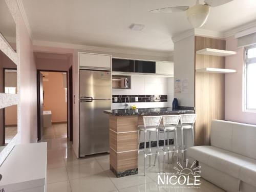 a kitchen with a refrigerator and some bar stools at Residencial Nicole in Florianópolis