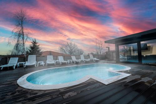 a swimming pool with chairs and a sunset at Hotel Winpalace in Arbanasi