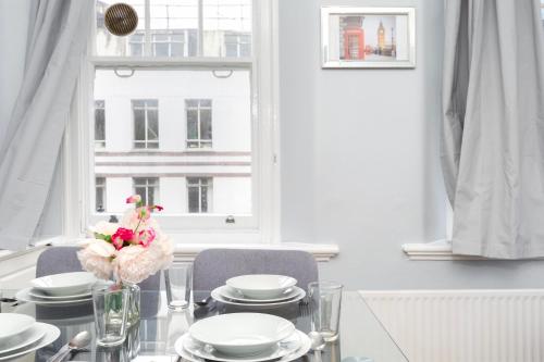 ロンドンにあるWells Street Central Apartmentsのダイニングテーブル(白い食器付)、窓