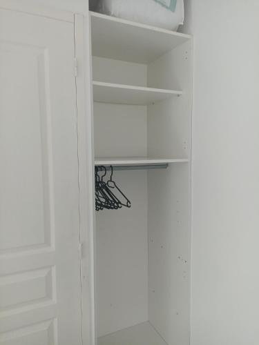 - un placard blanc avec des murs et des étagères blancs dans l'établissement Studio Vacances château Malo saint Malo, à Saint-Malo