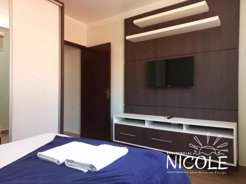 a bedroom with a bed with a tv on the wall at Residencial Nicole in Florianópolis