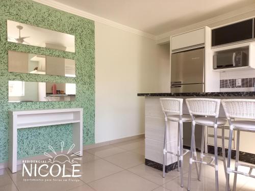 a kitchen with white and green walls and stools at Residencial Nicole in Florianópolis