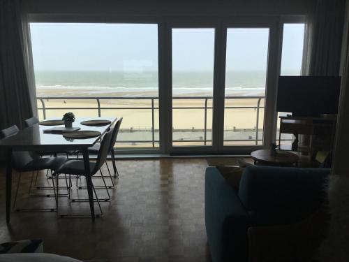 a living room with a table and a view of the beach at Royal Zeezicht Oostende in Ostend