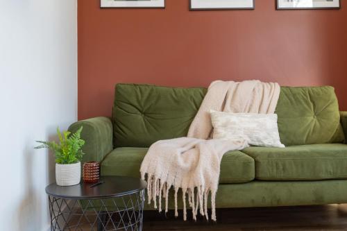 a green couch with a blanket on it in a living room at Eastside Capital Apartments in Belfast