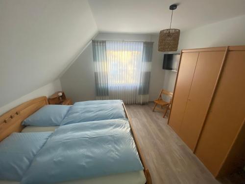 a bedroom with a bed with blue sheets and a window at Ferienwohnungen Schierbaum in Lembruch