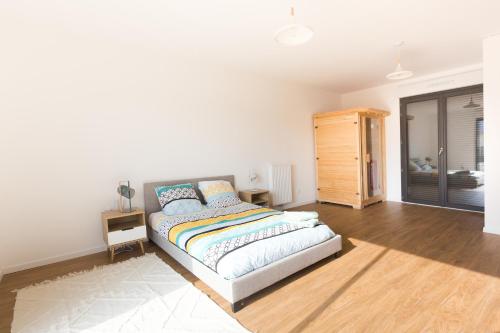 a white bedroom with a bed and a wooden cabinet at Sea house with Jaccuzy in Bretteville-sur-Ay