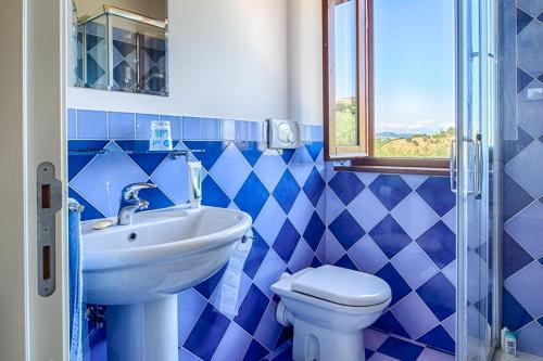 a blue tiled bathroom with a sink and a toilet at Casa Vitale in Carassai