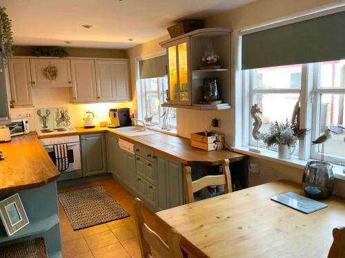 a kitchen with green cabinets and a wooden table at Romantic luxury Cottage right next to the ocean in Saint Abbs