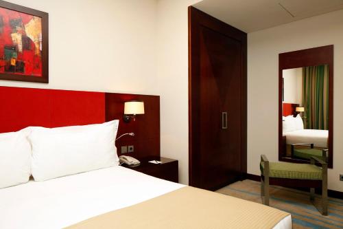 a hotel room with a bed and a mirror at Holiday Inn Olaya by IHG in Riyadh