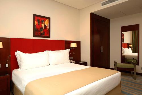 a hotel room with a large bed and a mirror at Holiday Inn Olaya by IHG in Riyadh