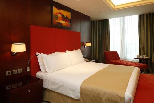a hotel room with a large bed and a red chair at Holiday Inn Olaya by IHG in Riyadh