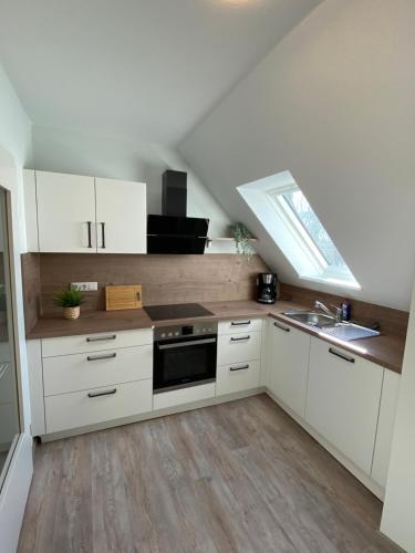 a kitchen with white cabinets and a sink and a window at Ferienwohnungen Schierbaum in Lembruch
