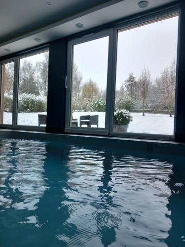 - une piscine avec de la neige à l'extérieur des fenêtres d'une maison dans l'établissement Chambre avec spa, piscine et sauna privatif, à Louches