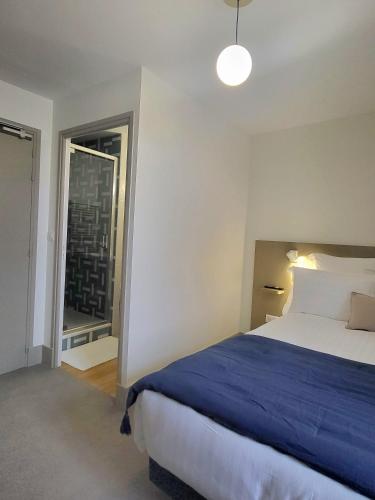 a bedroom with a large bed and a window at Mage hôtels - HÔTEL LA GRENETTE in Roanne