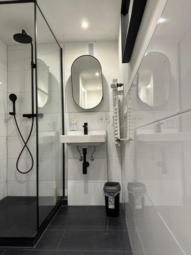 uma casa de banho com um chuveiro, um lavatório e um espelho. em 44qm Apartment in Pempelfort em Dusseldorf